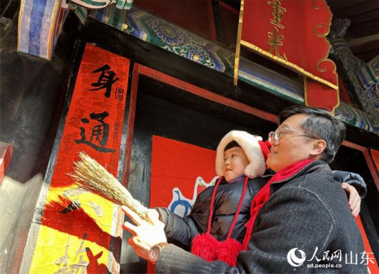 春節前，孔子后裔在孔府重光門前貼春聯。 人民網 喬姝攝
