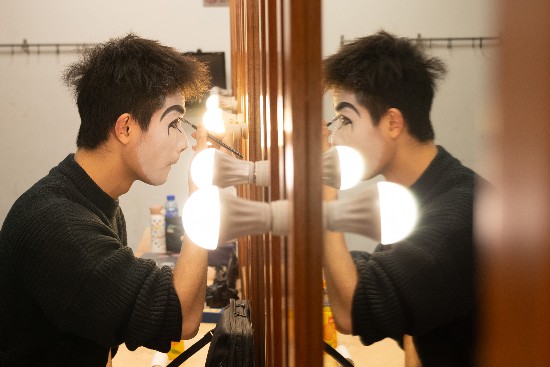 Backstage, male actors apply their own makeup. /CGTN